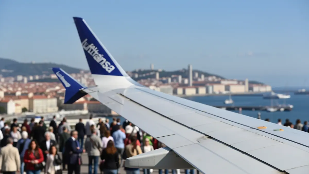 Imagem genérica de uma asa de avião da Lufthansa com a costa portuguesa e Lisboa ao fundo.