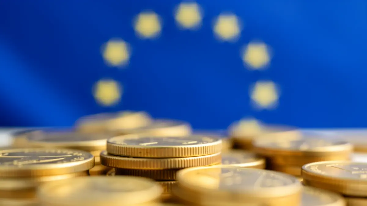 Generic image of European Union economic recovery funds, with blurred golden coins and a subtle EU flag motif in the background.